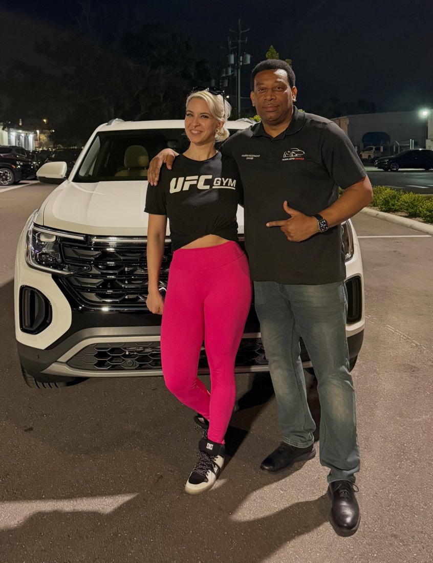 Martindale and a customer beside a white Chevrolet SUV in the evening