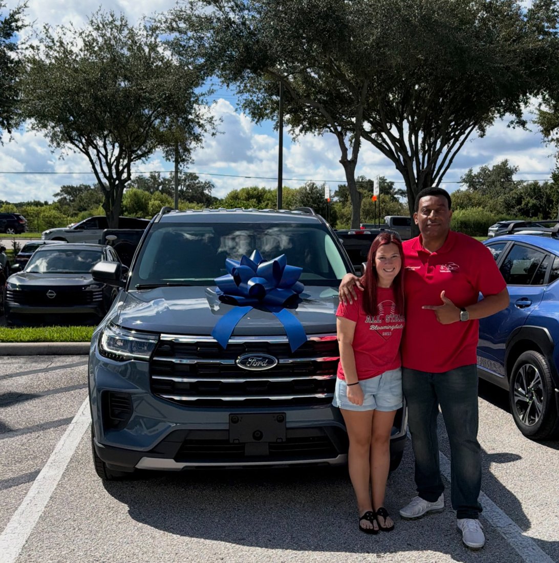 Martindale and a customer beside a Ford SUV with a blue bow