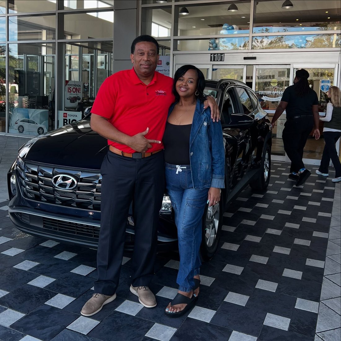 Martindale and a customer beside a Hyundai SUV at a dealership