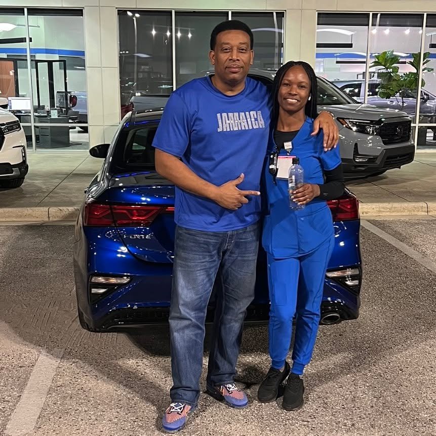Martindale and a customer beside a blue Kia outside a dealership