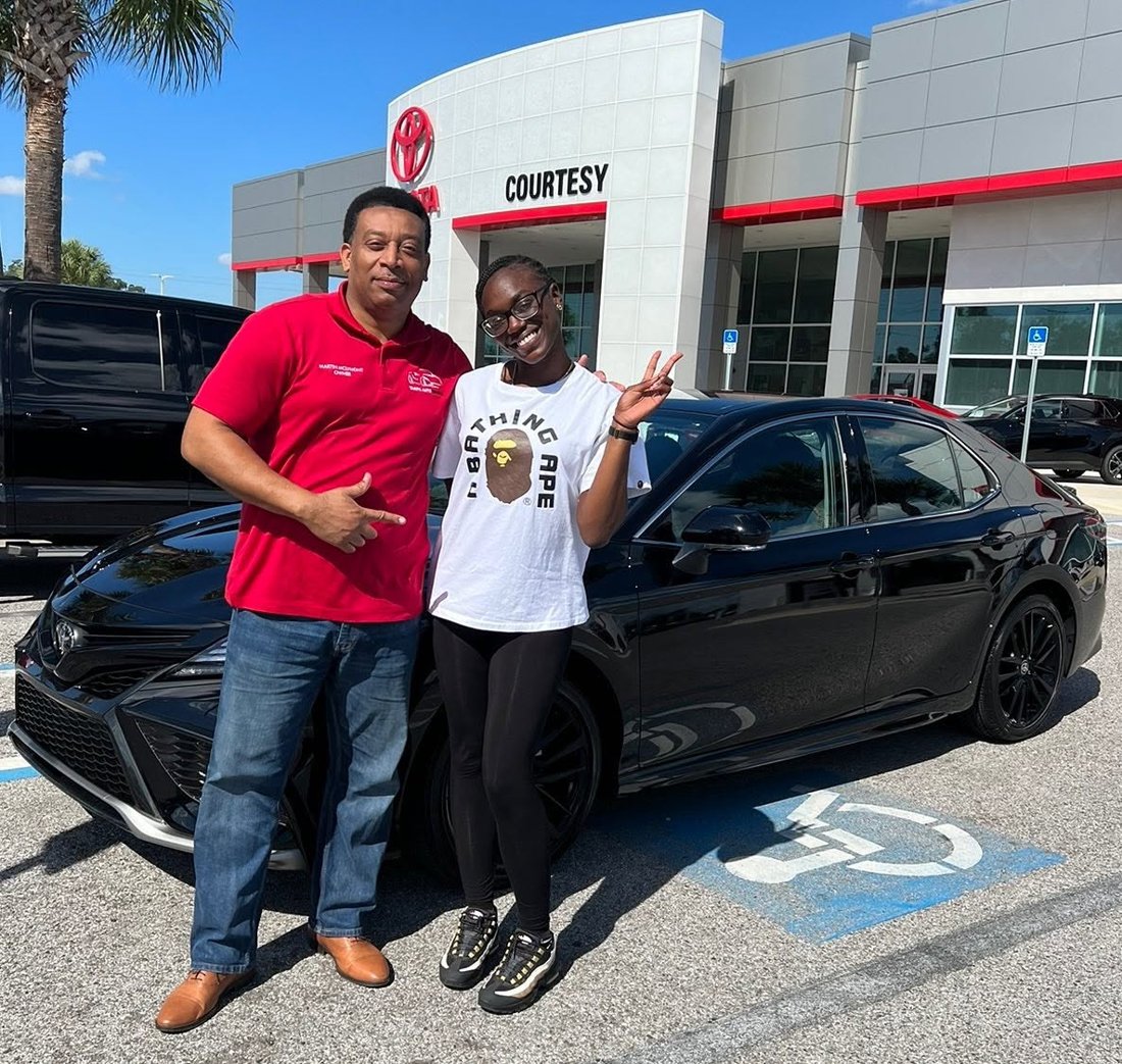 Martindale and a customer beside a black Toyota sedan