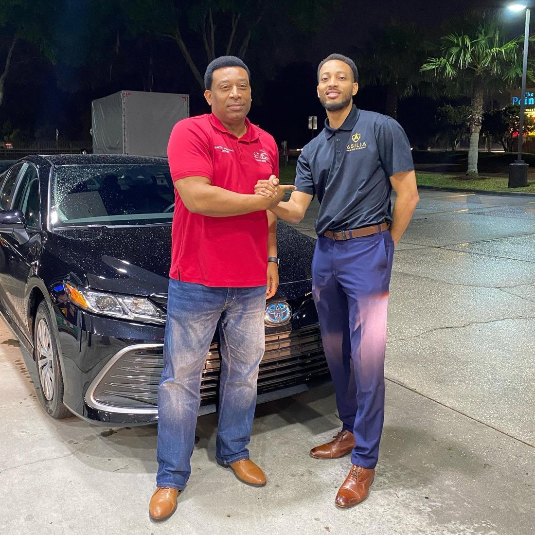 Martindale shaking hands with a customer beside a Toyota sedan